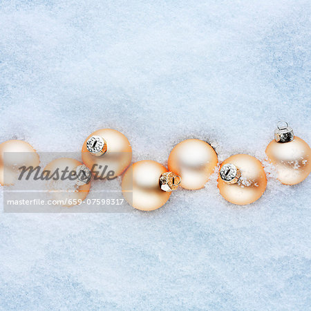 Apricot-coloured Christmas baubles in the snow