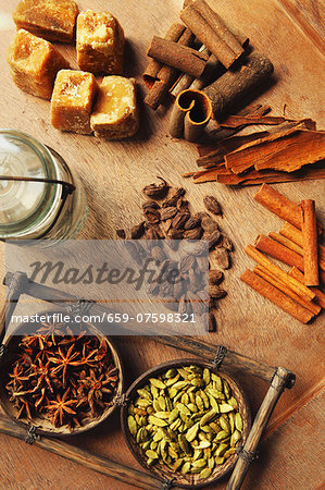 Assorted spices on a wooden table (cinnamon bark, cinnamon sticks, star anise, cardamom and palm sugar)