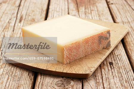 A chunk of Gruyère cheese on a chopping board