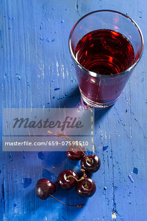 Cherries and cherry juice on a blue wooden tabletop