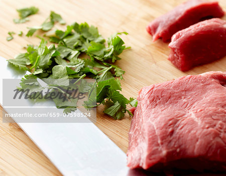 Raw Beef and Chopped Cilantro on a Wooden Cutting Board