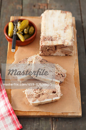 Pâté with chicken liver, partly sliced, and a small bowl of pickled gherkins