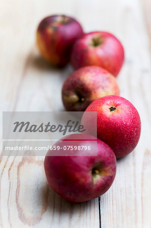 Five red organic apples on a wooden surfac