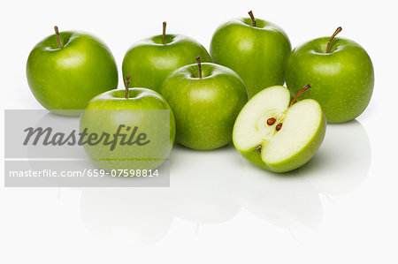 Several Granny Smith apples, whole and cut in half