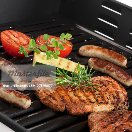 Pork steaks, sausages and vegetables on the grill