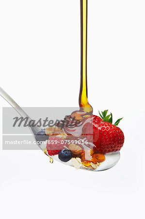 Honey Flowing on a Spoon with Berry Muesli