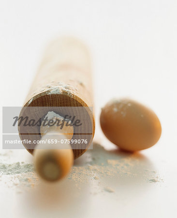 A still life featuring a rolling pin, flour and an egg