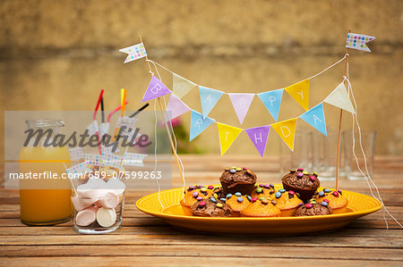 Muffins with chocolate beans, marshmallows and orange juice for a child's birthday