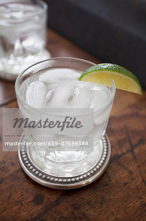 A glass of water with ice cubes and a slice of lime