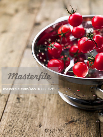 Cherry tomatoes falling into a colander