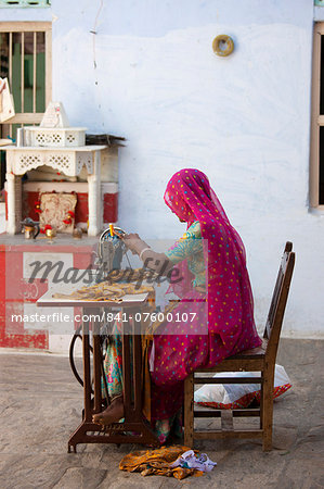 Indian woman wearing traditional Rajasthani sari works at home using sewing machine in village of Nimaj, Rajasthan, Northern India