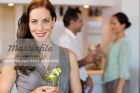 Smiling woman holding cocktail glass with friends at the bar