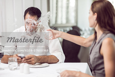 Woman throwing water on man in restaurant