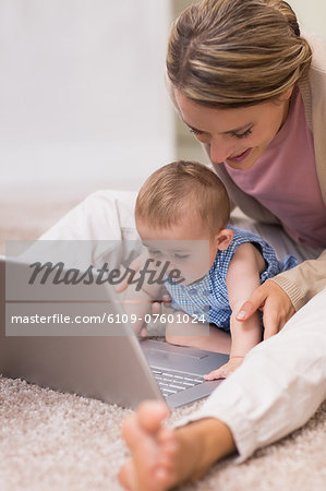 Beautiful mother teaching baby to use laptop