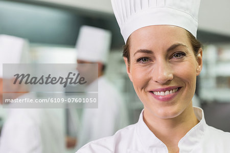 Smiling chef looking at camera with team working behind