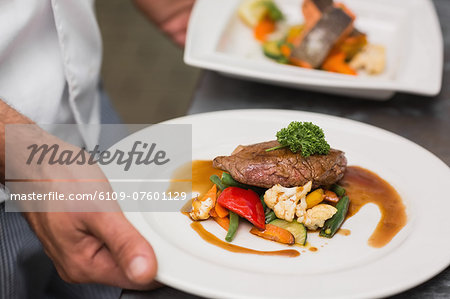 Chef holding steak dinner with vegetables and gravy