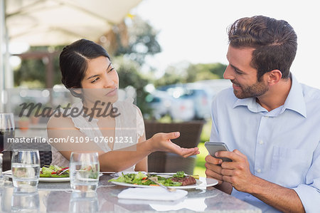 Annoyed woman taking phone from her date