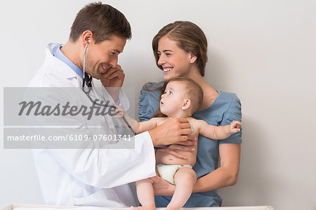 Handsome pediatrician checking baby boy held by his mother