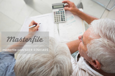 Senior couple using the calculator to pay bills