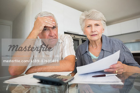 Worried couple paying their bills looking at camera