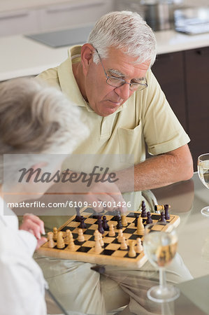 Senior couple playing chess and having white wine