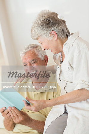 Senior man sitting on couch reading with partner