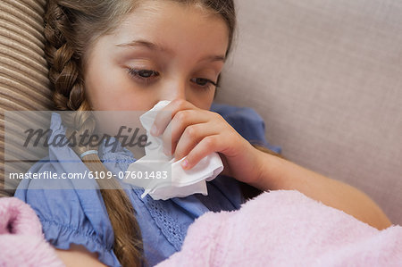 Young girl blowing nose with tissue paper