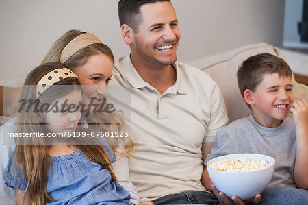 Cheerful family watching tv on sofa in living room