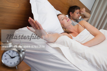 Couple in bed with alarm clock in foreground