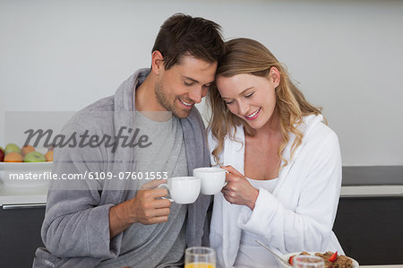 Young couple with coffee cups in kitchen