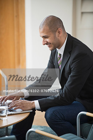 Smiling businessman working on laptop, Stockholm, Sweden