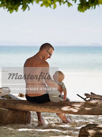 Father with baby on beach, Thailand