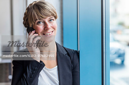 Young woman in office using cell phone, Stockholm, Sweden