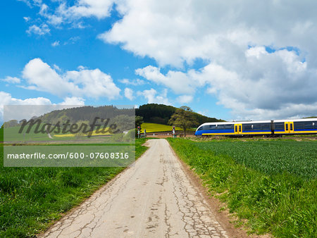 Farm road with train at railway crossing, Weser Hills,  North Rhine-Westphalia, Germany