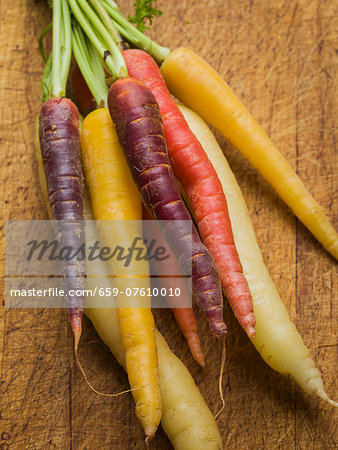 Multi-colored carrots in white, yellow, orange and red on a worn cutting board