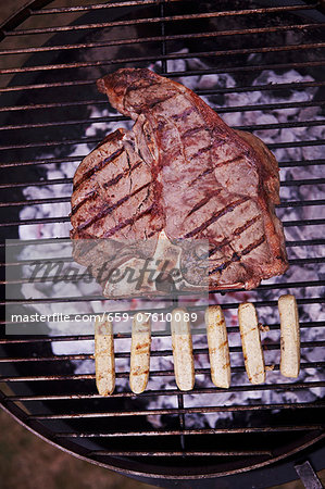 A T-bone steak and sausages on a barbecue A T-bone steak and sausages on a barbecue