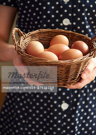 A woman holding a basket of fresh chicken's eggs