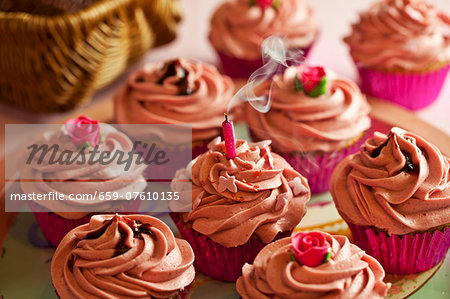 Cupcakes decorated with pink buttercream icing with a blown out, smoking candle Cupcakes decorated with pink buttercream icing with a blown out, smoking candle