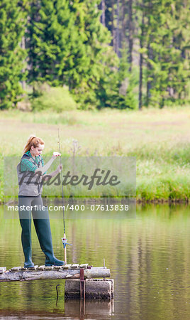 young woman fishing on pier at pond