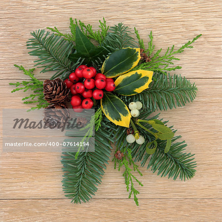 Christmas flora with holly, ivy mistletoe, fir and pine cones over oak wood background.
