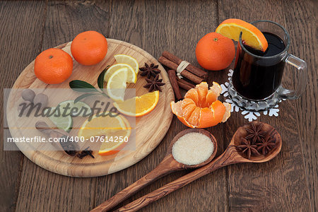 Christmas mulled wine ingredients of citrus fruit and spices over oak background.