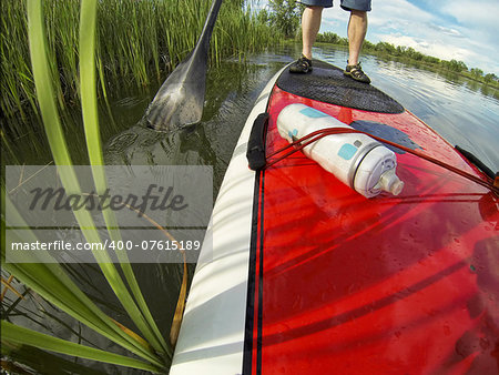 stand up paddling detail, a distorted wide angle view of a paddleboard near lake shore