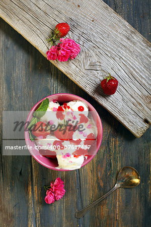 Ice cream with strawberries on old wooden table.