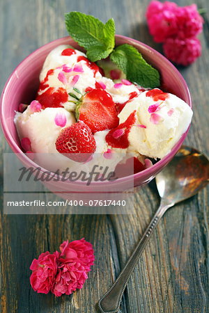 Cup with ice cream and strawberries on old wooden table.