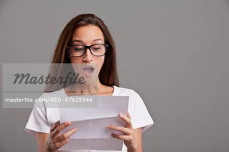 brunette young woman realizes that something amazing happened reading a white letter or document