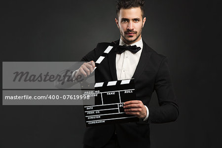 Portrait of a beautiful latin man with tuxedo and holding a clapboard
