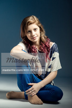 sitting studio fashion portrait of young beautiful girl with nice eyes on black