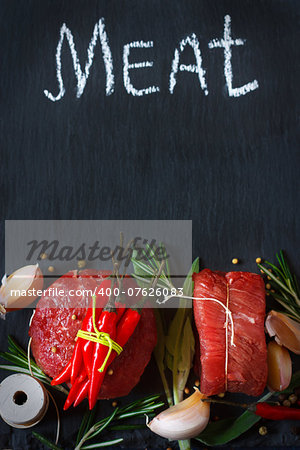 Fresh raw meat with spices and herbs on black.