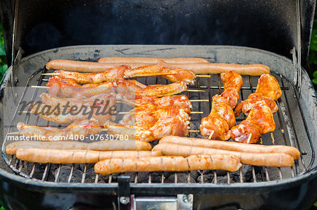 Sausages and chicken wings on the smoking grill barbeque