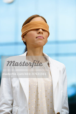 Concept of future and forecasting. Portrait of latina blindfolded businesswoman near office building